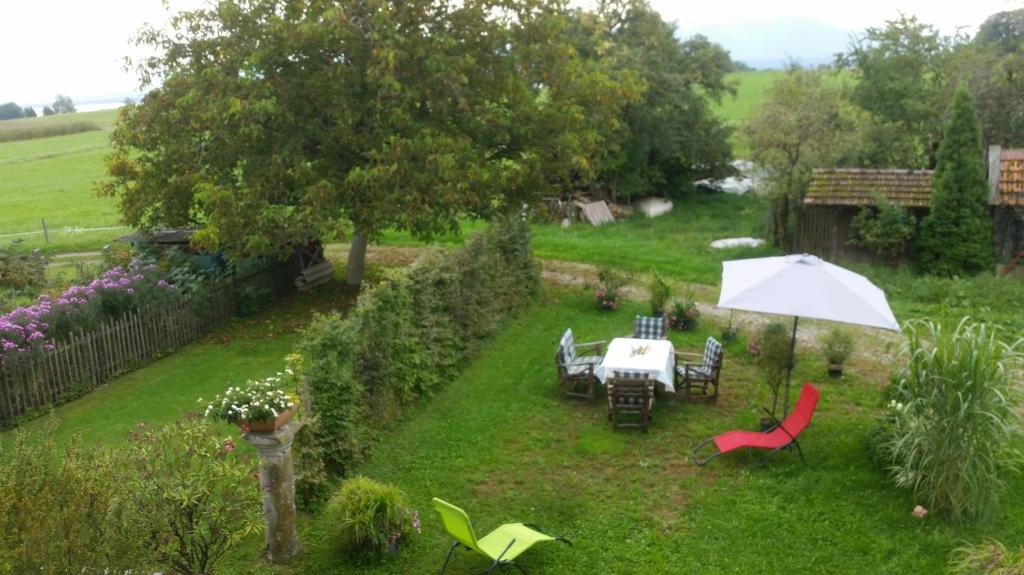 un giardino con tavolo, sedie e ombrellone di Ferienwohnung ChiemseeZeit :-) - Familie Lechermann a Gstadt am Chiemsee