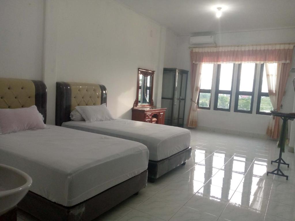 a bedroom with two beds and a sink and windows at Homestay Hilal Meulaboh Syariah RedPartner in Sua Dokata