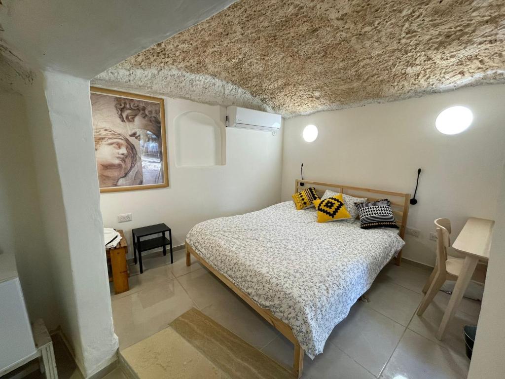 a bedroom with a bed and a painting on the wall at חצר הצ'אנס - בקתות להשראה in Almog