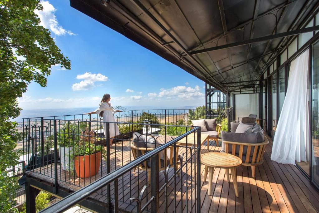 une femme debout sur un balcon donnant sur l'océan dans l'établissement Mizpe Hayamim by Isrotel Exclusive, à Rosh Pinna