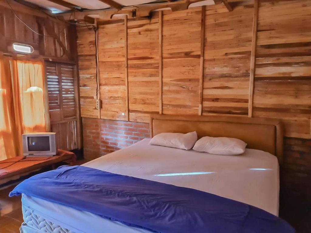 sypialnia z łóżkiem w pokoju z drewnianymi ścianami w obiekcie Family Guest House Lembang RedPartner w mieście Lembang