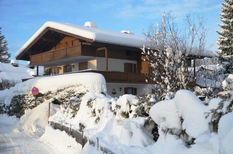 uma casa coberta de neve com árvores e arbustos em Ferienwohnung Moritz em Reit im Winkl
