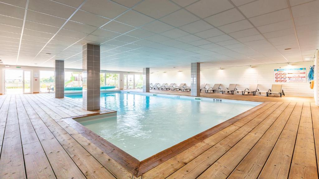 a pool in a large room with a wooden floor at Vacancéole - Les Chambres de la Baie in Roz-sur-Couesnon