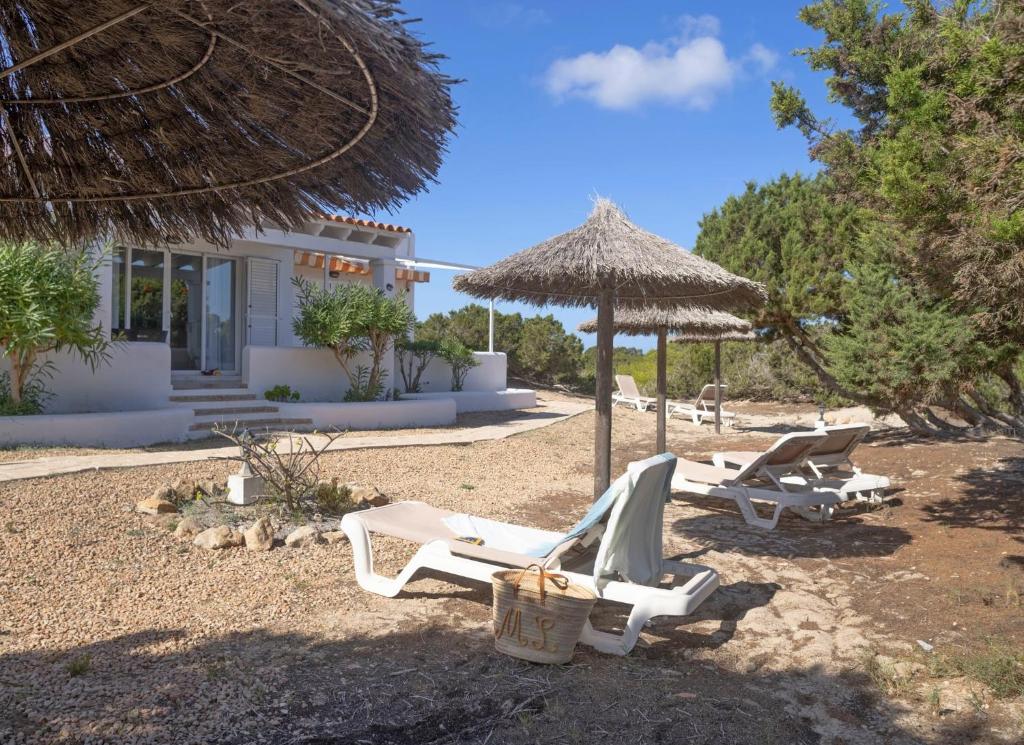 a group of chairs and an umbrella on a beach at Roquetes Bungalows Premium - Formentera Break in Es Pujols