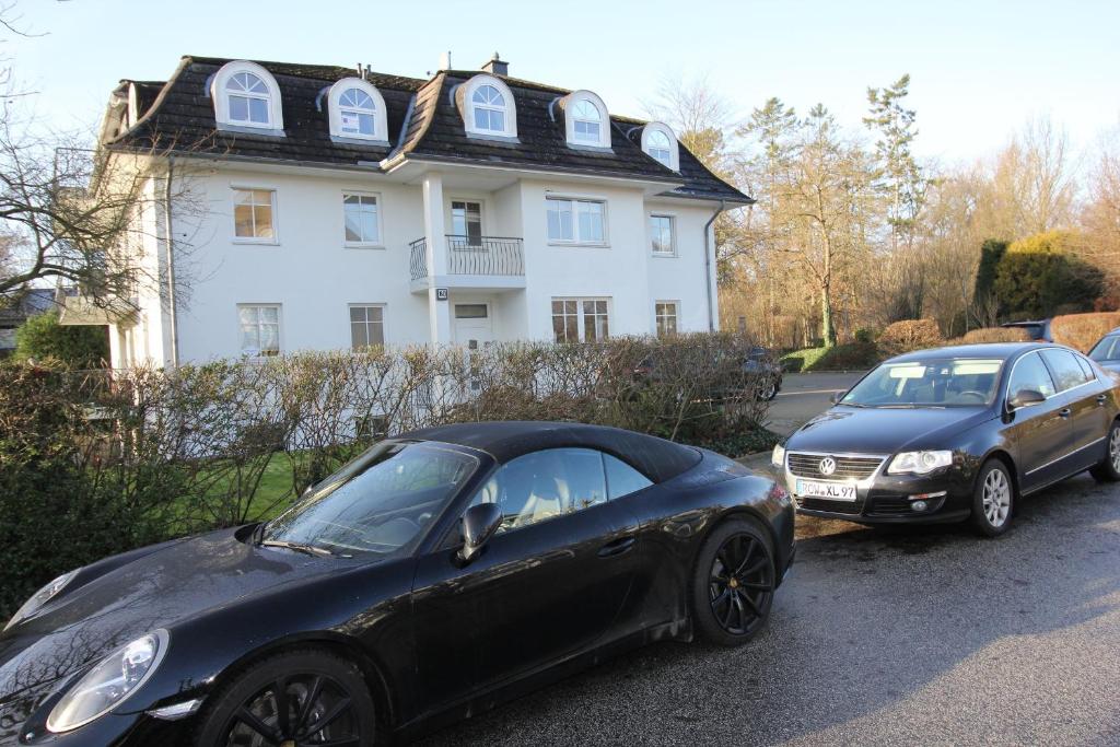 Deux voitures garées sur un parking en face d'une maison dans l'établissement Parkside No 8, à Timmendorfer Strand