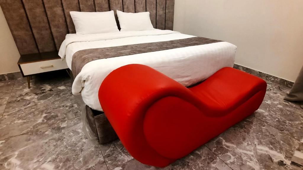 艾卜哈的住宿－جولدن نيو جوان - Golden New Gewan Hotel，一张红色椅子,坐在床边