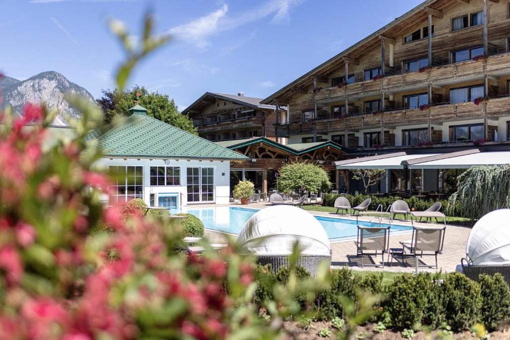 een hotel met een zwembad en stoelen en een gebouw bij Hotel Pirchnerhof in Reith im Alpbachtal