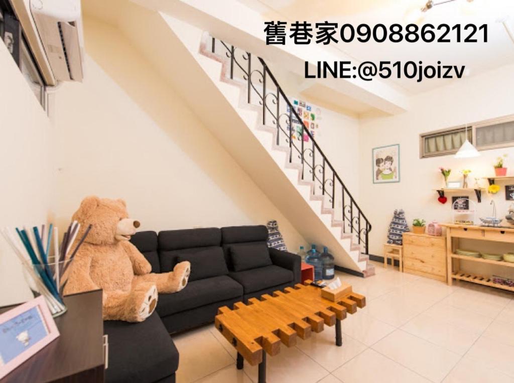 uma sala de estar com um sofá preto e um urso de peluche em Old Alley Home B&B em Tainan