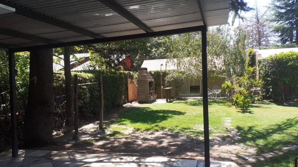 a backyard with a wooden pergola and grass at Pequeña casa en chacras de coria in Chacras de Coria