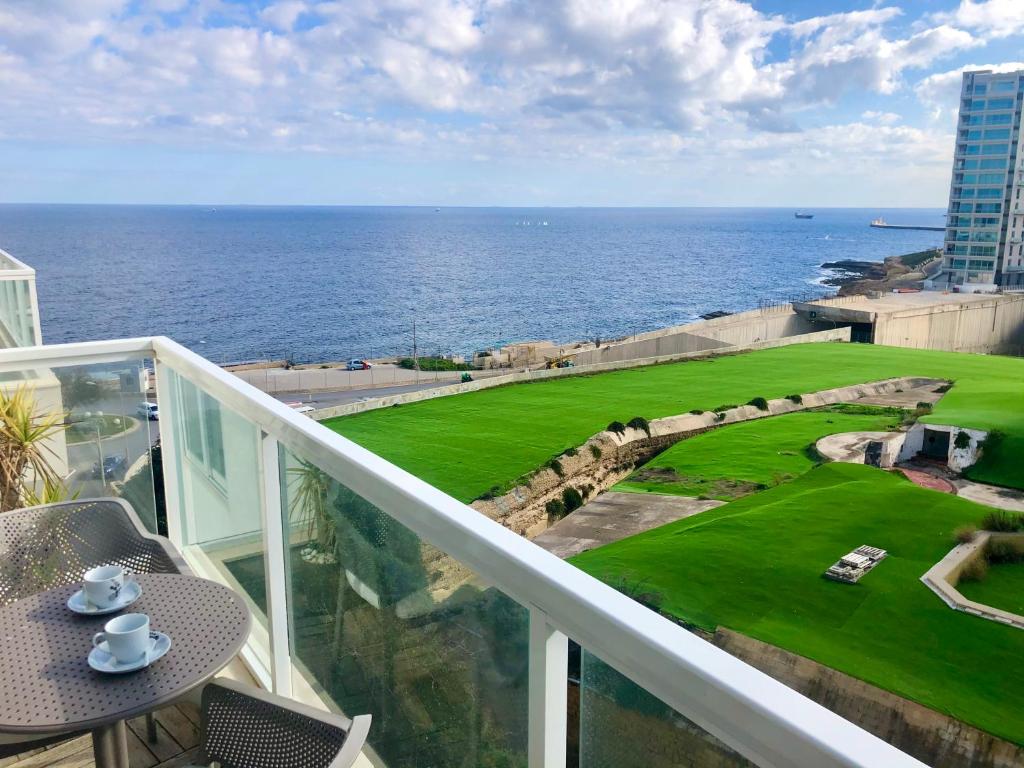 a balcony with a view of a golf course on the ocean at Stylish Seaview Apartment In a Prime Location in Sliema