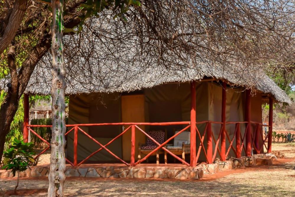 eine kleine Hütte mit einem Strohdach und einem Baum in der Unterkunft Lake Jipe Eco Lodge in Tsavo West National Park