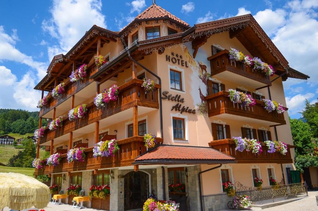 un gran edificio con flores en los balcones en Hotel Stella Alpina en Moena