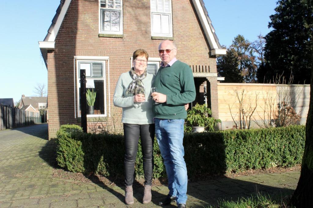 un hombre y una mujer parados frente a una casa en B&B Pullemans en Wijster