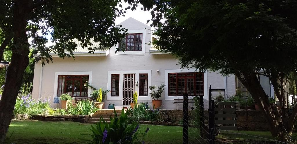 a white house with a garden in front of it at The Gate Guesthouse in Clarens