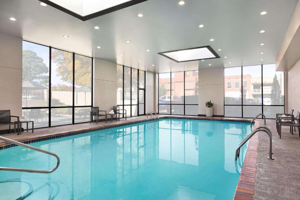 a large swimming pool in a building with windows at Wyndham Fort Smith City Center in Fort Smith