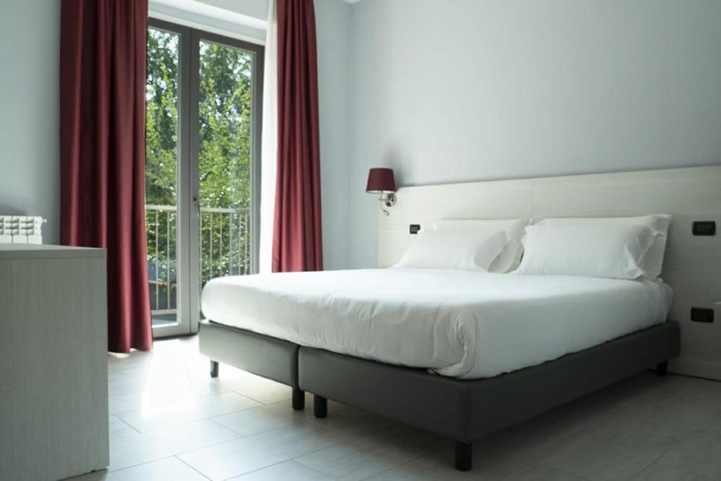 um quarto com uma grande cama branca com cortinas vermelhas em Hotel Pone em Sesto San Giovanni