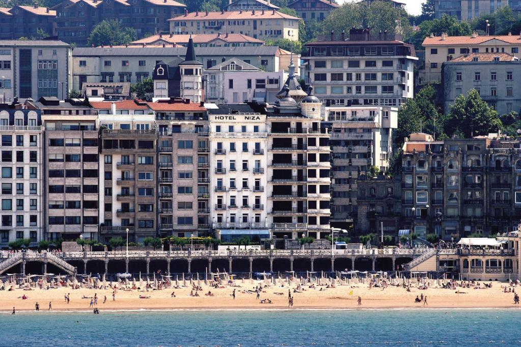 a view of a beach with buildings and people at Hotel Niza in San Sebastián