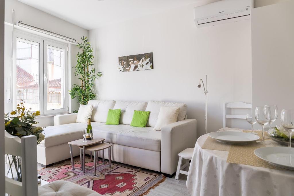 a white living room with a white couch and green pillows at 2 Bedroom house and Garden Lounge in Sintra