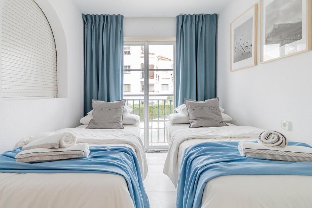 2 łóżka w pokoju z niebieskimi zasłonami w obiekcie Lovely 2 Bedroom Apartment w/ large garden + pools w mieście Benalmádena