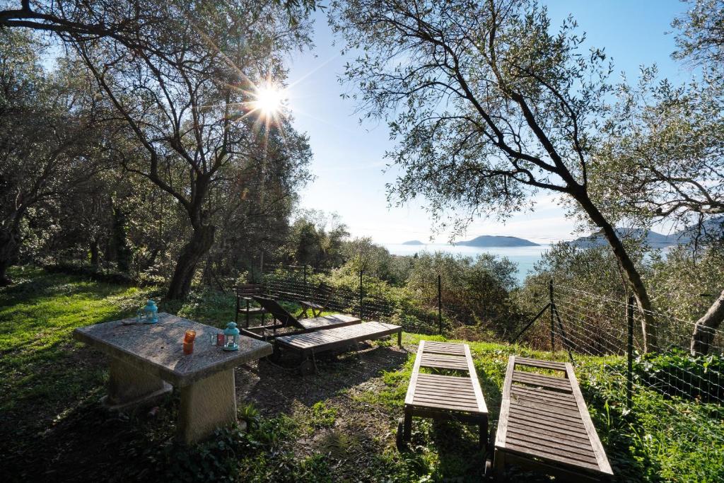 a picnic table and two benches in a field at Casa Conte Picedi appartamento Luna in Lerici
