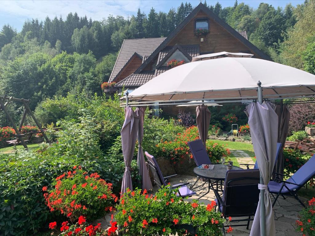 a patio with an umbrella and chairs and flowers at Agropajda in Sokolec