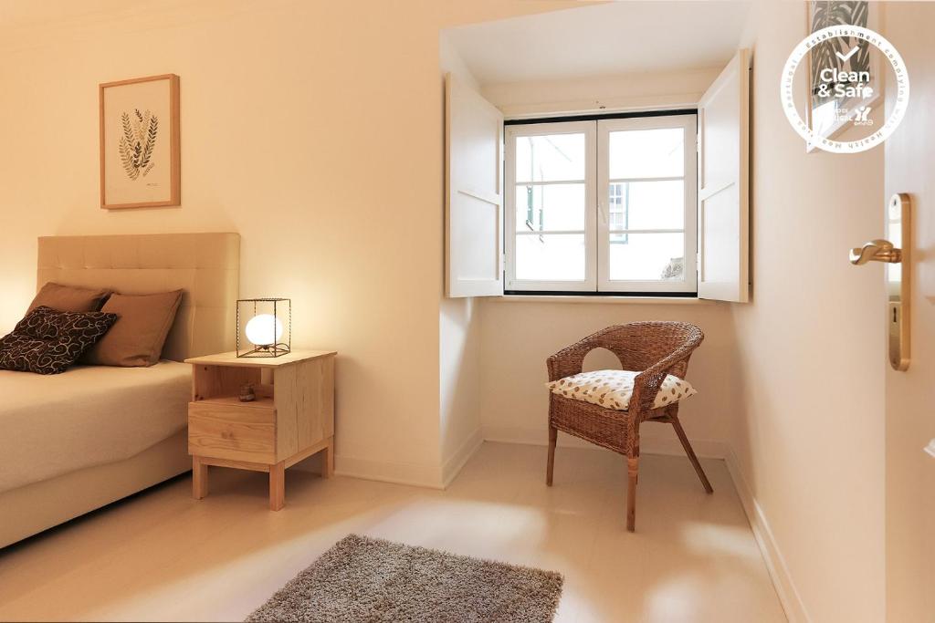 リスボンにあるAlfama Prestige by Homingのベッドルーム1室(ベッド1台、椅子、窓付)