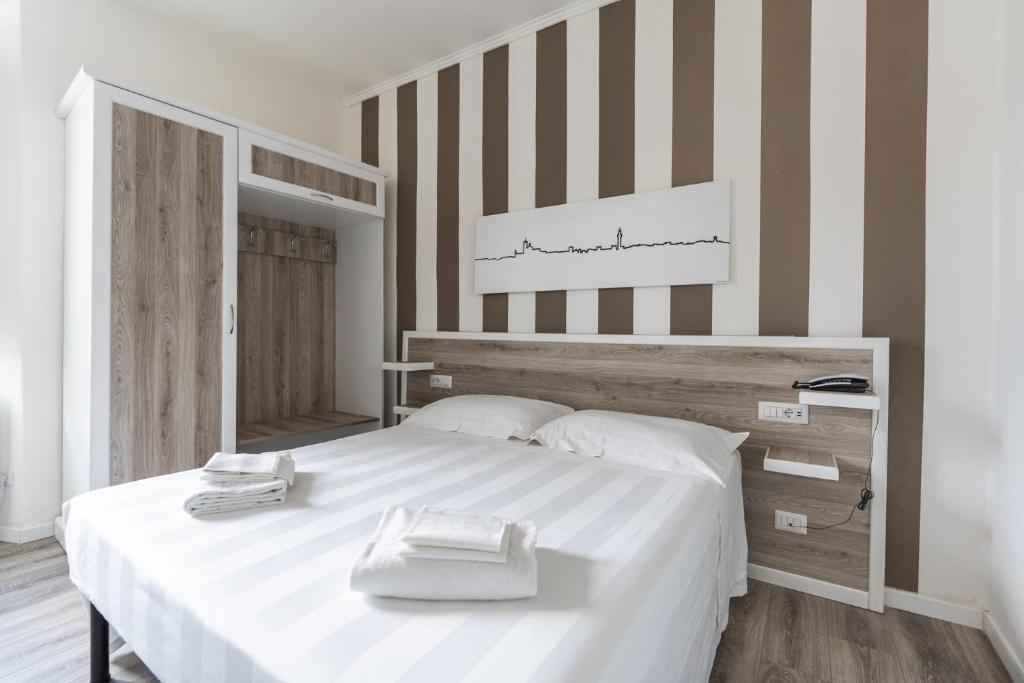 a bedroom with a large white bed with a striped wall at Albergo Centrale in Siena