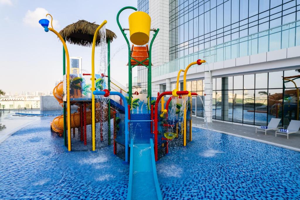 Novotel Jumeirah Village Triangle في دبي: زحليقة مائية في مسبح في مبنى