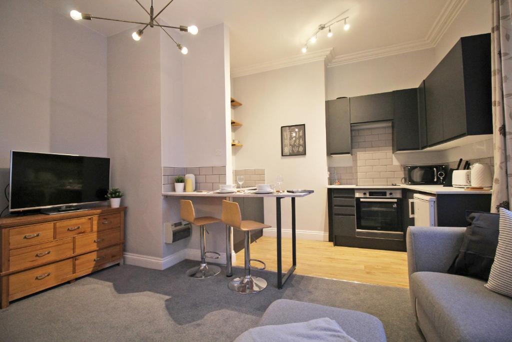 een woonkamer met een tafel en een keuken bij Lovely 1 Bed serviced apartment in Cambridgeshire in Ely