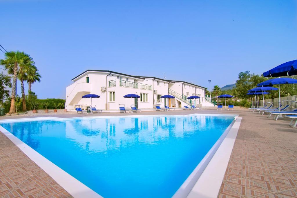 uma piscina com água azul e guarda-sóis azuis em Brezza dell'Alento em Marina di Casalvelino