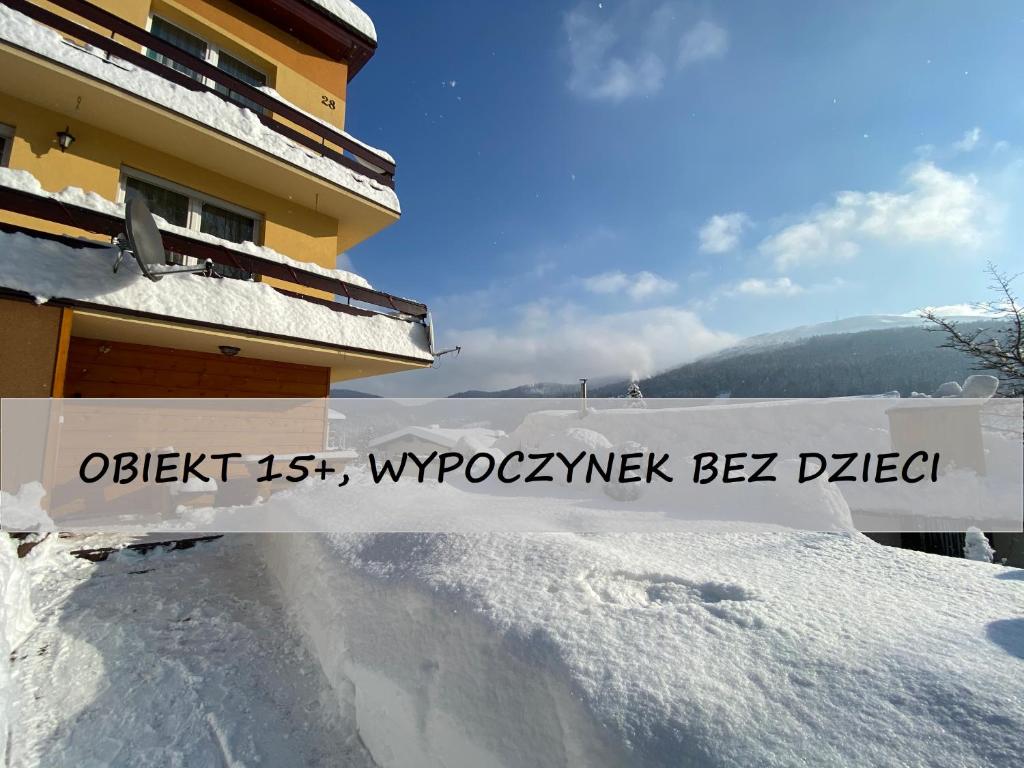 シュチルクにあるCztery Pory Roku Pokoje Gościnneの雪の建物側の看板