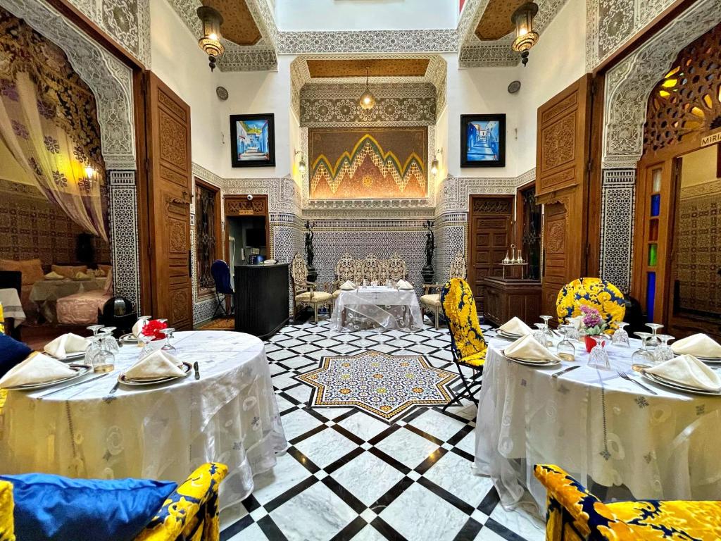 a restaurant with two tables with white table cloth at Riad Dar Guennoun in Fès