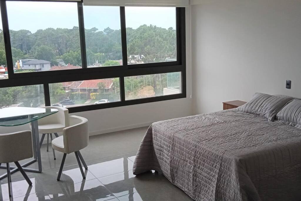 1 dormitorio con cama, mesa y ventanas en Monomabiente amplio con piscina, en Punta del Este