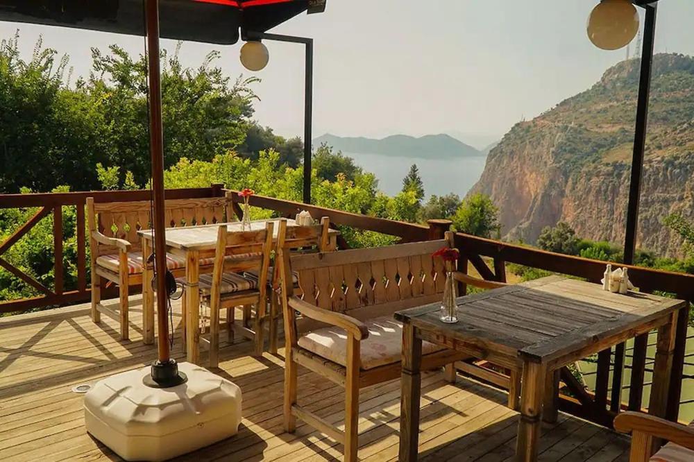 a wooden deck with a table and chairs and an umbrella at ONUR MOTEL FARALYA FETHİYE in Faralya