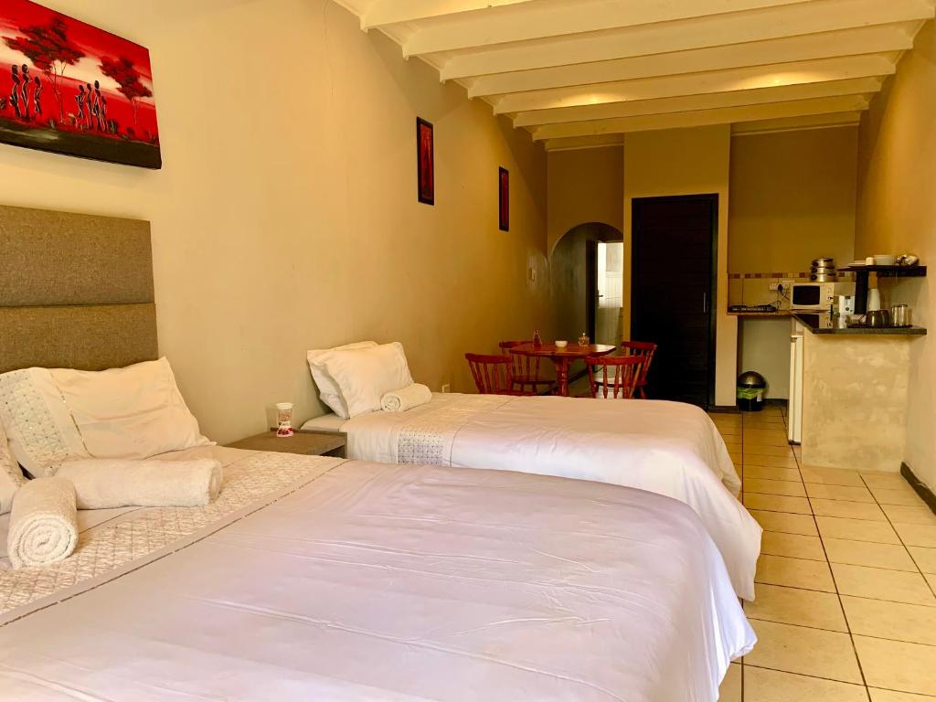 a hotel room with two beds and a table at The Eden Lodge Boksburg in Boksburg