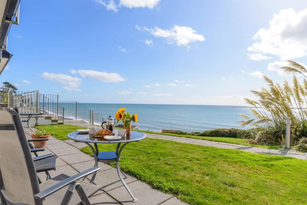 a patio with a table and chairs and the ocean at Beach Retreat - Mount Brioni in Downderry