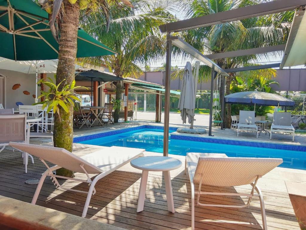 una piscina con sedie, ombrelloni, tavolo e tavolo da biliardo di Cristal do Guarujá Pousada a Guarujá