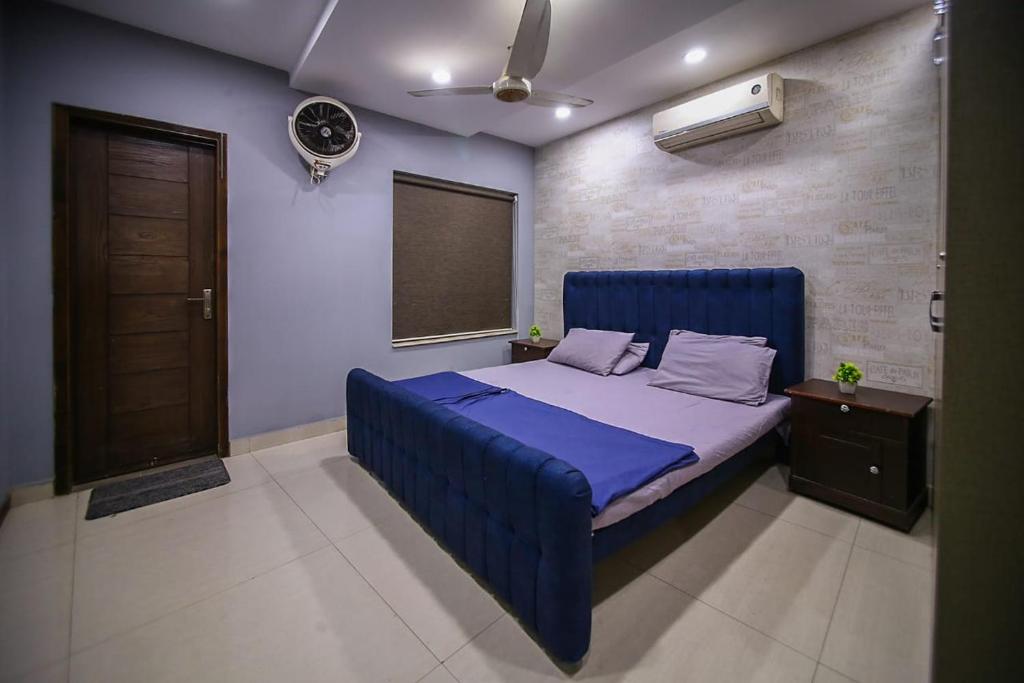 a bedroom with a blue bed and a window at Two Bedrooms Apartment Near DHA & Airport in Lahore