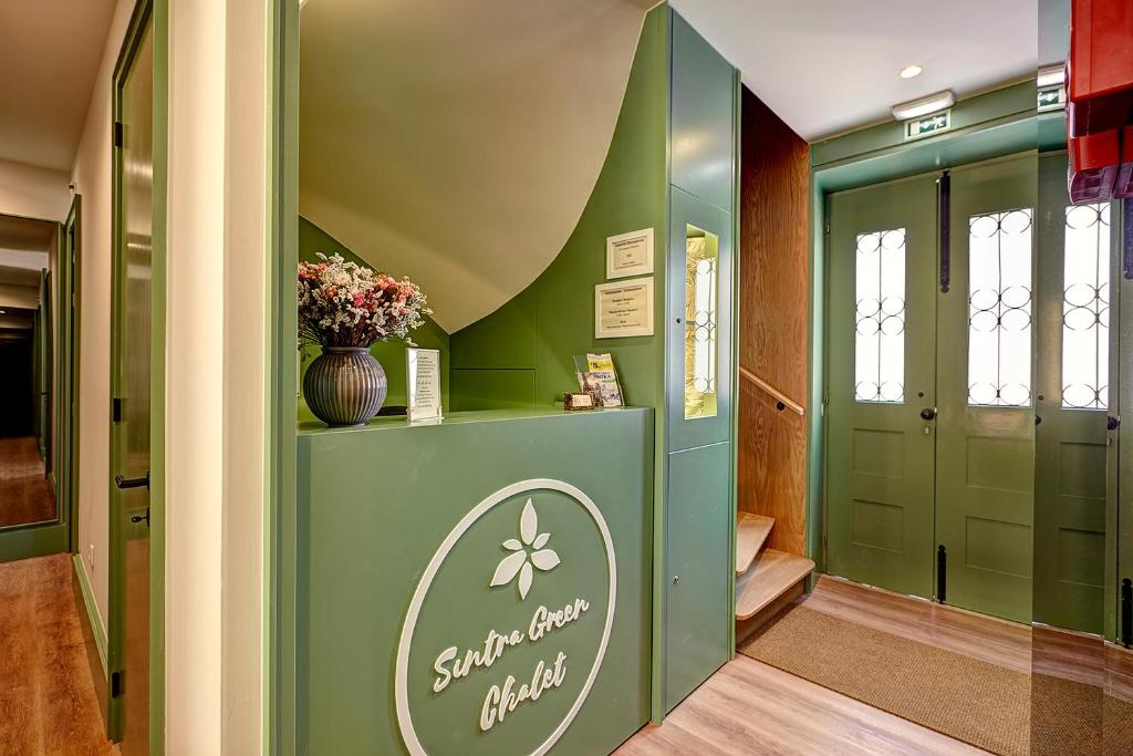 a hallway with a green door with a vase of flowers at Sintra Green Chalet Bed & Breakfast in Sintra