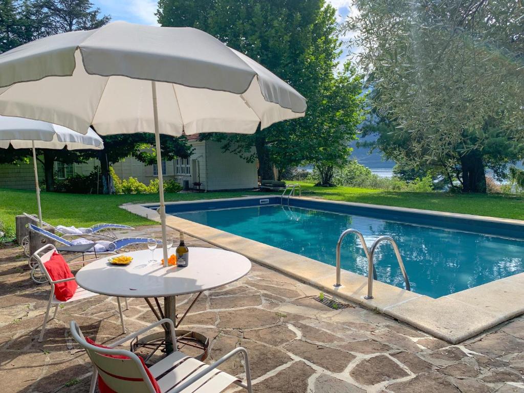 a table with an umbrella next to a swimming pool at Pitti Villa in Lierna