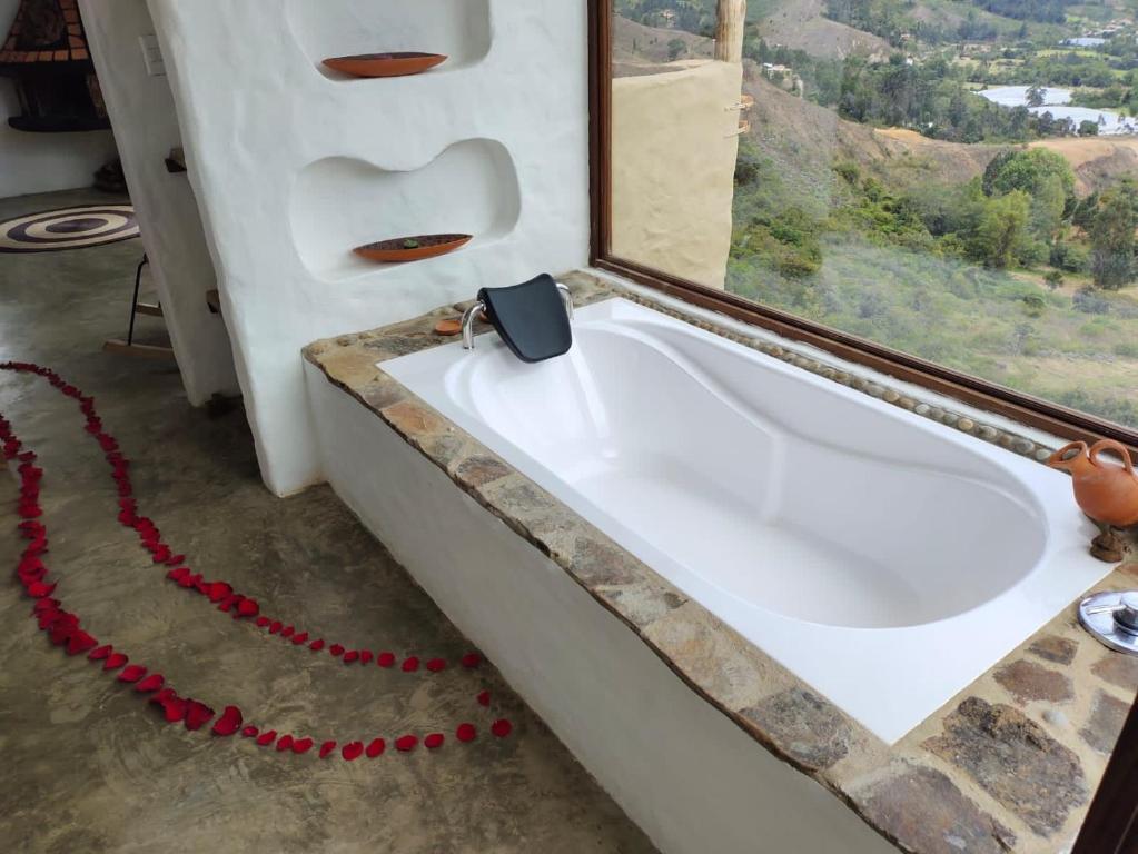 a bath tub in a room with a window at Paraiso de Arcilla - Suite & Glamping in Ráquira