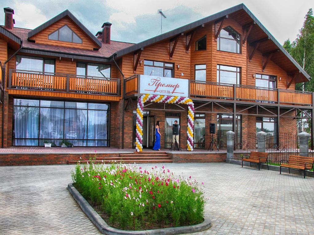 un gran edificio de madera con flores delante en Premier Hotel, en Gorodets