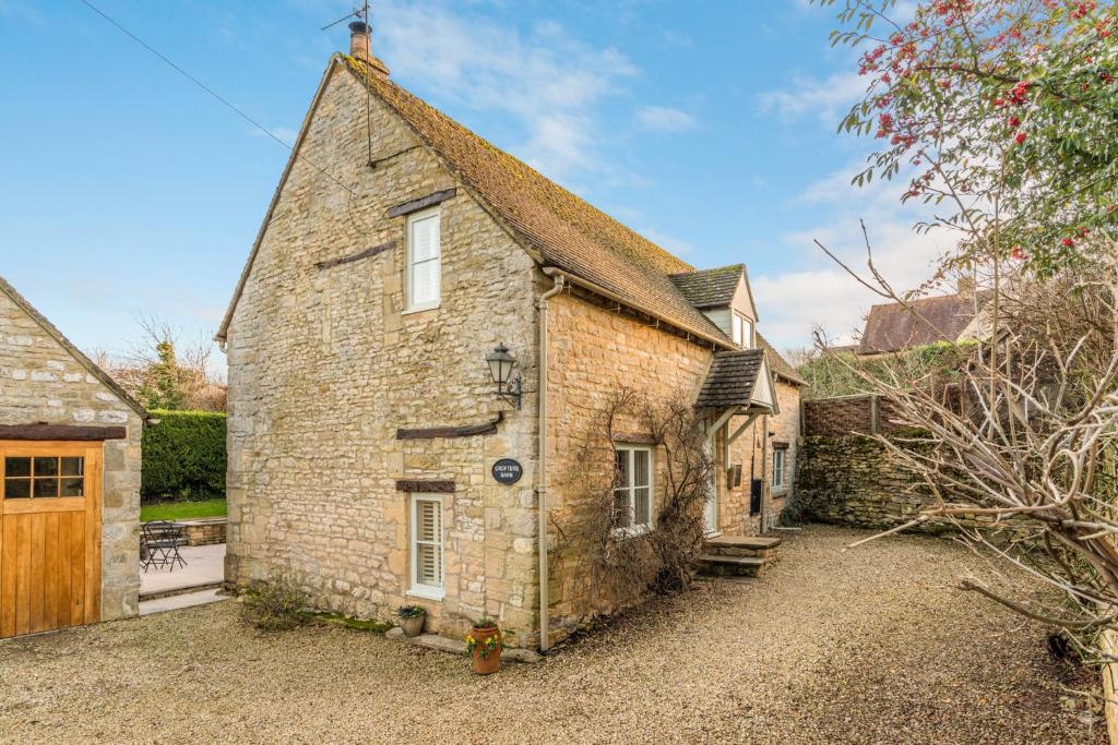 an old stone house with a gravel driveway at Crofter's Barn in Chipping Norton