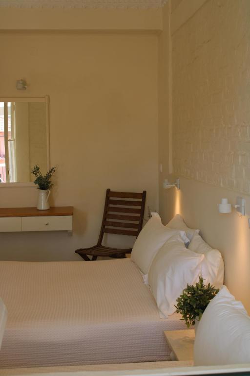 a bedroom with two beds and a chair at Zefiros Traditional Hotel in Paleokastritsa