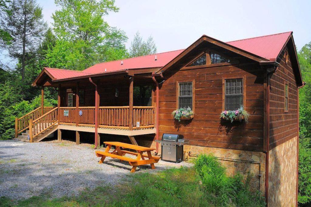 a large wooden cabin with a picnic table and a bench at Lucky Cub Cabin in Sevierville