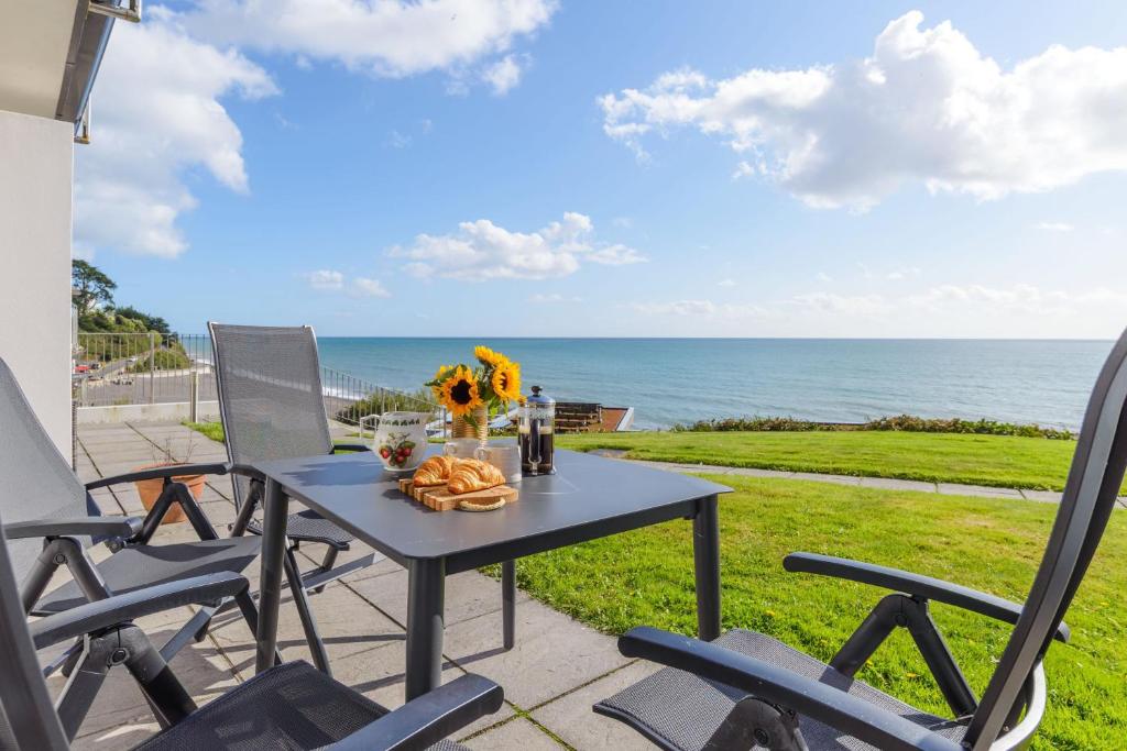 einen Tisch und Stühle auf einer Terrasse mit Meerblick in der Unterkunft Mi Casa Su Casa - Mount Brioni in Downderry