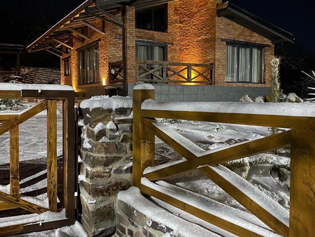 Verkhniy Koropets的住宿－BrickWood，雪中房子前面的木栅栏