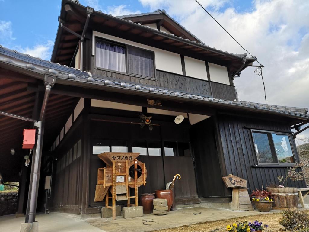 un bâtiment noir et blanc avec une maison dans l'établissement 古民家ゲストハウスひまわり, à Isa