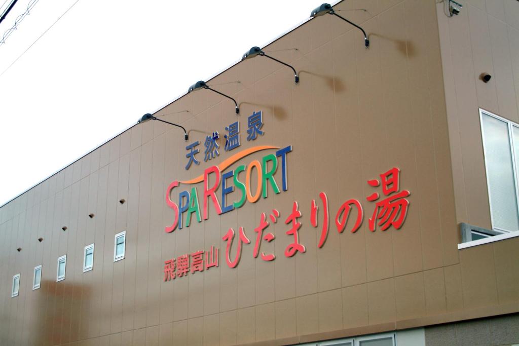 een bord voor een restaurant aan de zijkant van een gebouw bij Natural Onsen Hostel Hidamari no Yu in Takayama
