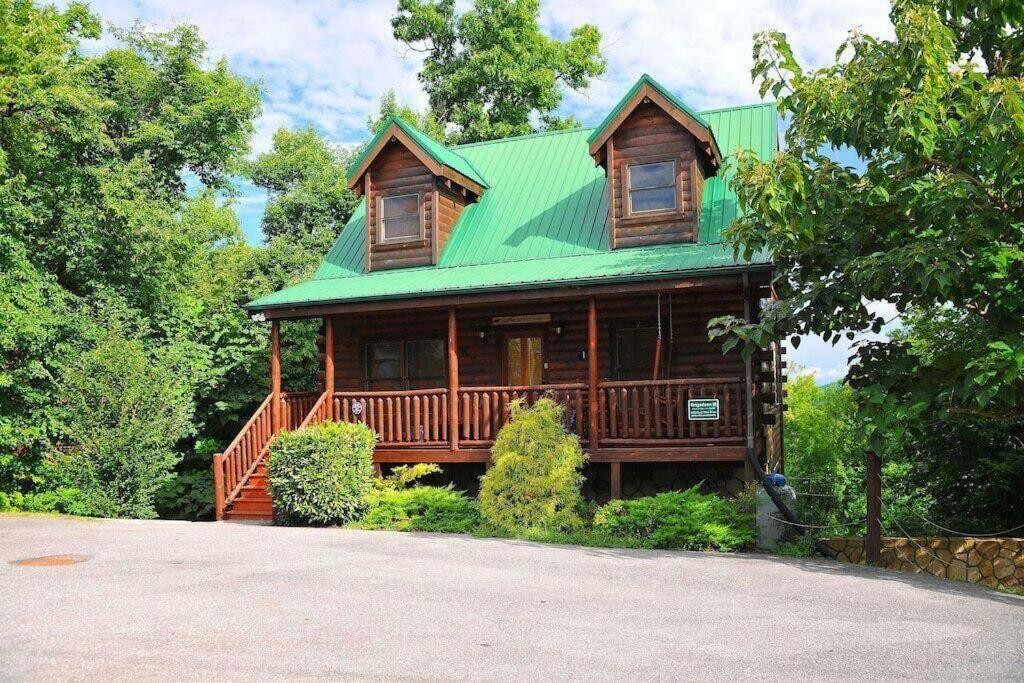 Casa de madera grande con techo verde en Sleepy Willow Cabin, en Sevierville